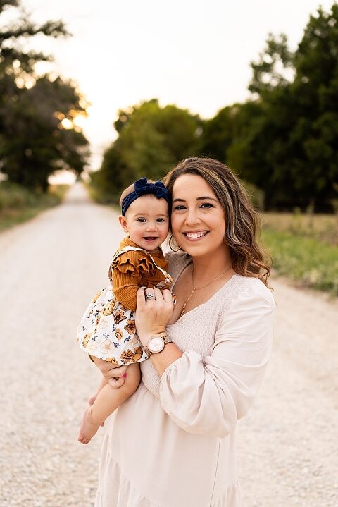 Oden Family walking together on a gravel road during a September photo session
Parents smiling at their children while standing on a country road
Children running and laughing down a gravel road in golden light
Family hugging closely with the soft glow of evening behind them