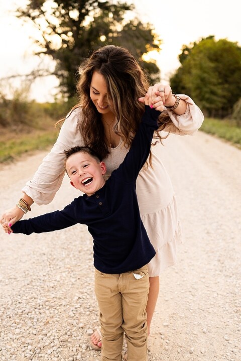 Oden Family walking together on a gravel road during a September photo session
Parents smiling at their children while standing on a country road
Children running and laughing down a gravel road in golden light
Family hugging closely with the soft glow of evening behind them