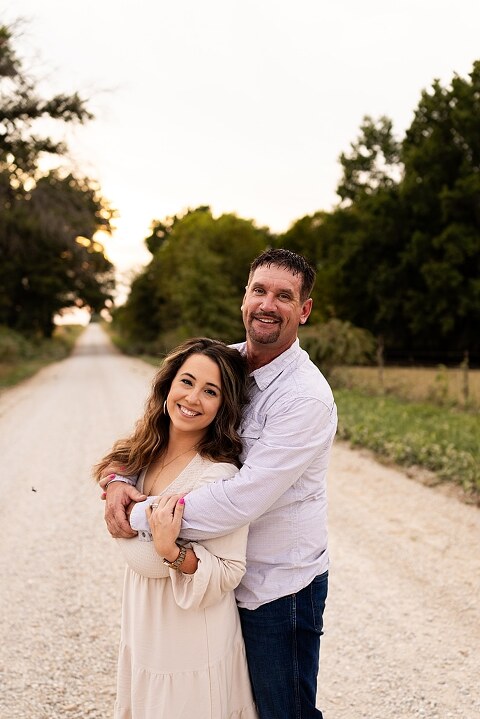 Oden Family walking together on a gravel road during a September photo session
Parents smiling at their children while standing on a country road
Children running and laughing down a gravel road in golden light
Family hugging closely with the soft glow of evening behind them