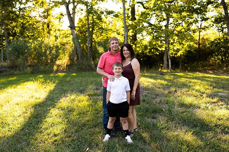 Family walking together through a field in High Hill Missouri
Parents smiling at their child while standing on a gravel road
Child laughing and making a silly face during a family session
Family holding hands in tall grass with warm evening light
Parents hugging their child while standing on a quiet country road