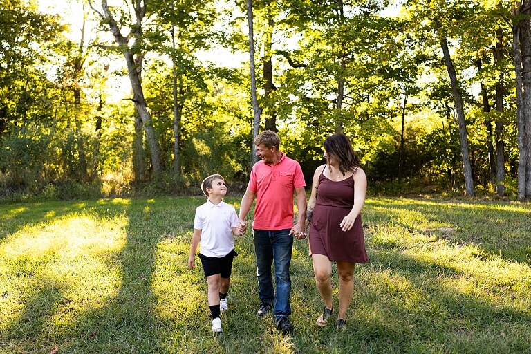 Family walking together through a field in High Hill Missouri
Parents smiling at their child while standing on a gravel road
Child laughing and making a silly face during a family session
Family holding hands in tall grass with warm evening light
Parents hugging their child while standing on a quiet country road