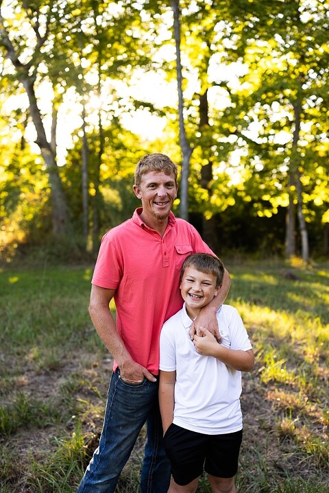 Family walking together through a field in High Hill Missouri
Parents smiling at their child while standing on a gravel road
Child laughing and making a silly face during a family session
Family holding hands in tall grass with warm evening light
Parents hugging their child while standing on a quiet country road