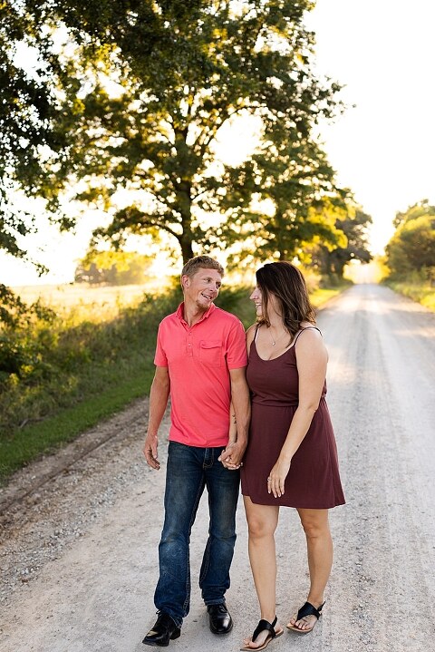 Family walking together through a field in High Hill Missouri
Parents smiling at their child while standing on a gravel road
Child laughing and making a silly face during a family session
Family holding hands in tall grass with warm evening light
Parents hugging their child while standing on a quiet country road