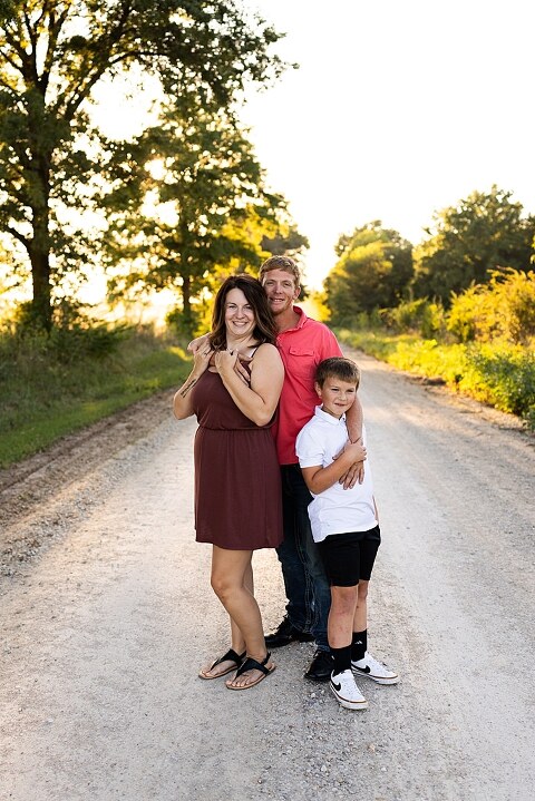 Family walking together through a field in High Hill Missouri
Parents smiling at their child while standing on a gravel road
Child laughing and making a silly face during a family session
Family holding hands in tall grass with warm evening light
Parents hugging their child while standing on a quiet country road