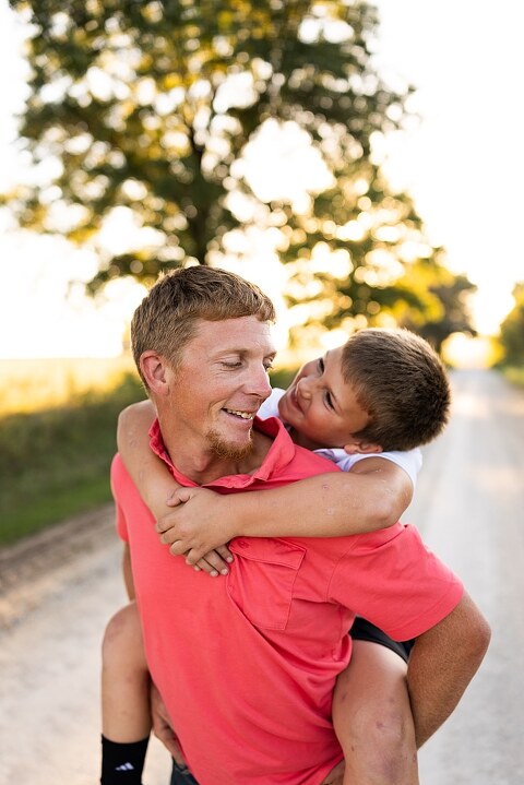Family walking together through a field in High Hill Missouri
Parents smiling at their child while standing on a gravel road
Child laughing and making a silly face during a family session
Family holding hands in tall grass with warm evening light
Parents hugging their child while standing on a quiet country road