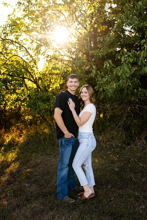 Tyler and Grace standing on a sunlit path at Towne Park during their engagement session.
Couple laughing together in an open field at Towne Park.
Tyler and Grace holding hands along a wooded trail with soft golden light behind them.
Close–up of the couple smiling at each other during their engagement session.
Engagement ring photo taken at Towne Park with natural greenery in the background.