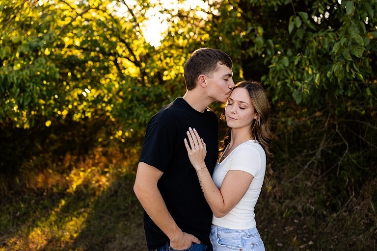 Tyler and Grace standing on a sunlit path at Towne Park during their engagement session.
Couple laughing together in an open field at Towne Park.
Tyler and Grace holding hands along a wooded trail with soft golden light behind them.
Close–up of the couple smiling at each other during their engagement session.
Engagement ring photo taken at Towne Park with natural greenery in the background.