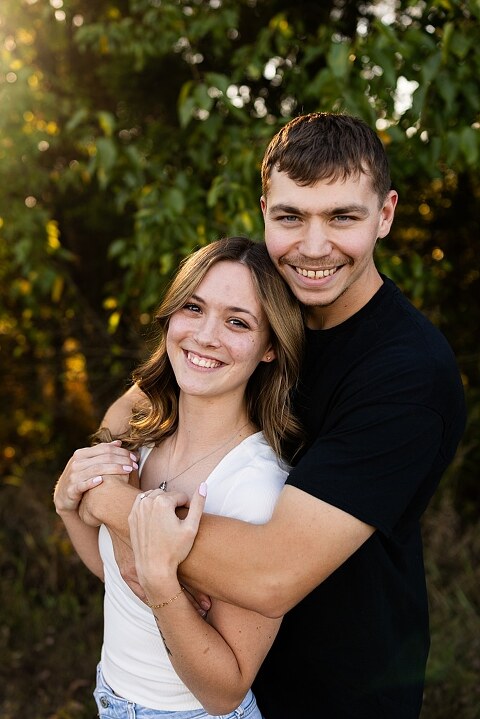 Tyler and Grace standing on a sunlit path at Towne Park during their engagement session.
Couple laughing together in an open field at Towne Park.
Tyler and Grace holding hands along a wooded trail with soft golden light behind them.
Close–up of the couple smiling at each other during their engagement session.
Engagement ring photo taken at Towne Park with natural greenery in the background.