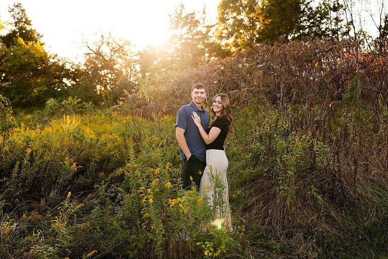 Tyler and Grace standing on a sunlit path at Towne Park during their engagement session.
Couple laughing together in an open field at Towne Park.
Tyler and Grace holding hands along a wooded trail with soft golden light behind them.
Close–up of the couple smiling at each other during their engagement session.
Engagement ring photo taken at Towne Park with natural greenery in the background.