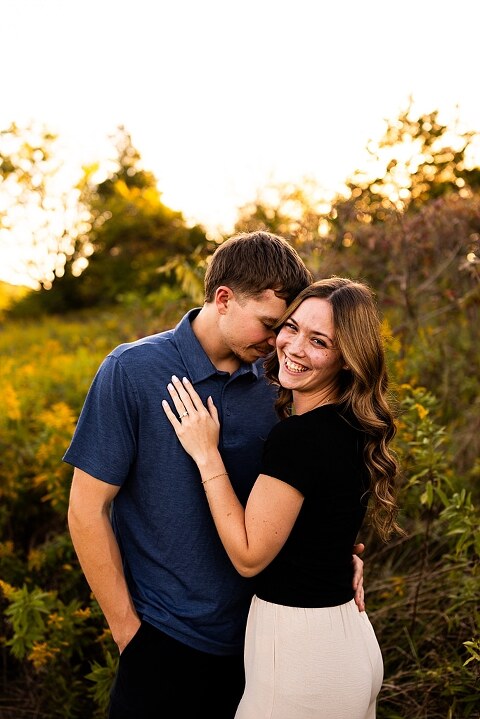 Tyler and Grace standing on a sunlit path at Towne Park during their engagement session.
Couple laughing together in an open field at Towne Park.
Tyler and Grace holding hands along a wooded trail with soft golden light behind them.
Close–up of the couple smiling at each other during their engagement session.
Engagement ring photo taken at Towne Park with natural greenery in the background.