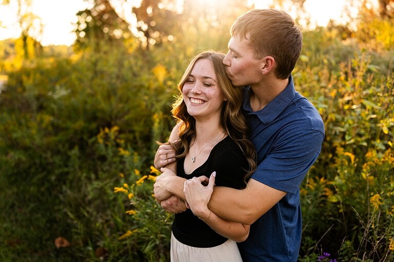 Tyler and Grace standing on a sunlit path at Towne Park during their engagement session.
Couple laughing together in an open field at Towne Park.
Tyler and Grace holding hands along a wooded trail with soft golden light behind them.
Close–up of the couple smiling at each other during their engagement session.
Engagement ring photo taken at Towne Park with natural greenery in the background.