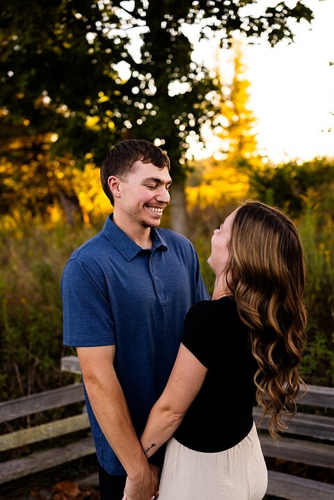 Tyler and Grace standing on a sunlit path at Towne Park during their engagement session.
Couple laughing together in an open field at Towne Park.
Tyler and Grace holding hands along a wooded trail with soft golden light behind them.
Close–up of the couple smiling at each other during their engagement session.
Engagement ring photo taken at Towne Park with natural greenery in the background.