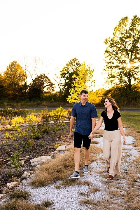Tyler and Grace standing on a sunlit path at Towne Park during their engagement session.
Couple laughing together in an open field at Towne Park.
Tyler and Grace holding hands along a wooded trail with soft golden light behind them.
Close–up of the couple smiling at each other during their engagement session.
Engagement ring photo taken at Towne Park with natural greenery in the background.