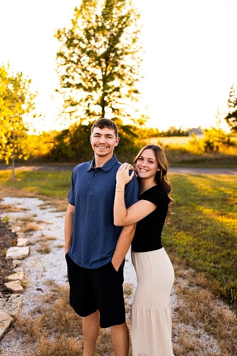 Tyler and Grace standing on a sunlit path at Towne Park during their engagement session.
Couple laughing together in an open field at Towne Park.
Tyler and Grace holding hands along a wooded trail with soft golden light behind them.
Close–up of the couple smiling at each other during their engagement session.
Engagement ring photo taken at Towne Park with natural greenery in the background.