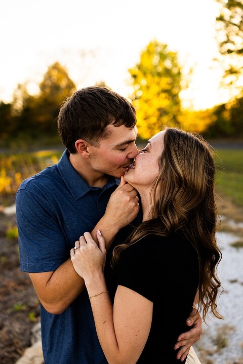 Tyler and Grace standing on a sunlit path at Towne Park during their engagement session.
Couple laughing together in an open field at Towne Park.
Tyler and Grace holding hands along a wooded trail with soft golden light behind them.
Close–up of the couple smiling at each other during their engagement session.
Engagement ring photo taken at Towne Park with natural greenery in the background.