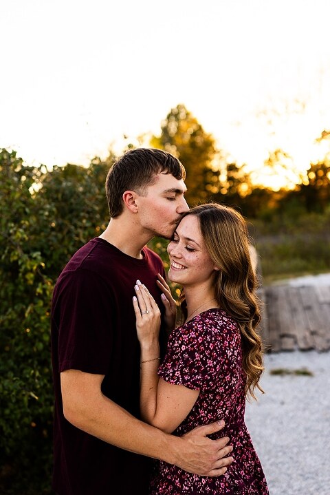 Tyler and Grace standing on a sunlit path at Towne Park during their engagement session.
Couple laughing together in an open field at Towne Park.
Tyler and Grace holding hands along a wooded trail with soft golden light behind them.
Close–up of the couple smiling at each other during their engagement session.
Engagement ring photo taken at Towne Park with natural greenery in the background.