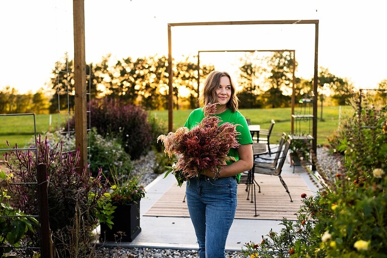 Aimie standing in her flower garden in High Hill Missouri surrounded by colorful blooms.
Close–up of Aimie gently holding freshly cut flowers from her garden.
Wide view of the flower farm with rows of vibrant summer flowers.
Aimie smiling while arranging flowers during her garden session.
Hands holding a bouquet of freshly picked flowers in soft natural light.