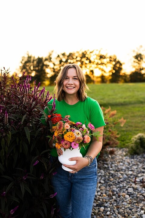 Aimie standing in her flower garden in High Hill Missouri surrounded by colorful blooms.
Close–up of Aimie gently holding freshly cut flowers from her garden.
Wide view of the flower farm with rows of vibrant summer flowers.
Aimie smiling while arranging flowers during her garden session.
Hands holding a bouquet of freshly picked flowers in soft natural light.