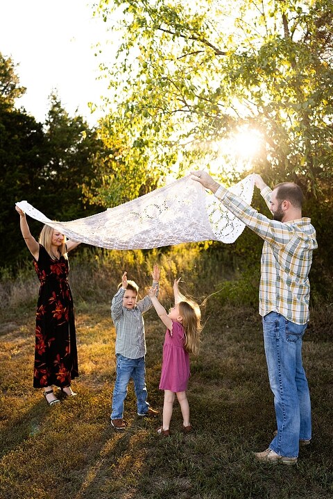 Family standing together at Towne Park during a golden afternoon.
Kids smiling and posing on a gravel path at Towne Park.
Parents laughing while holding their children during the session.
Children running through a sunny field at Towne Park.
Family cuddled together on a grassy patch beneath tall trees.