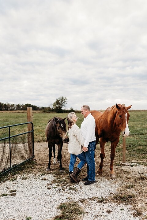 Couple standing together on their new country property during golden hour.
Tina and Jimmy laughing together beside a tall tree line.
Couple posing with one of their farm animals in soft evening light.
Tina and Jimmy walking hand in hand across their open field.
Close-up of the couple smiling with their animals nearby.