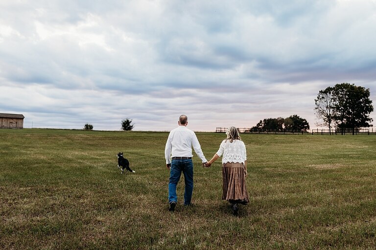 Couple standing together on their new country property during golden hour.
Tina and Jimmy laughing together beside a tall tree line.
Couple posing with one of their farm animals in soft evening light.
Tina and Jimmy walking hand in hand across their open field.
Close-up of the couple smiling with their animals nearby.
