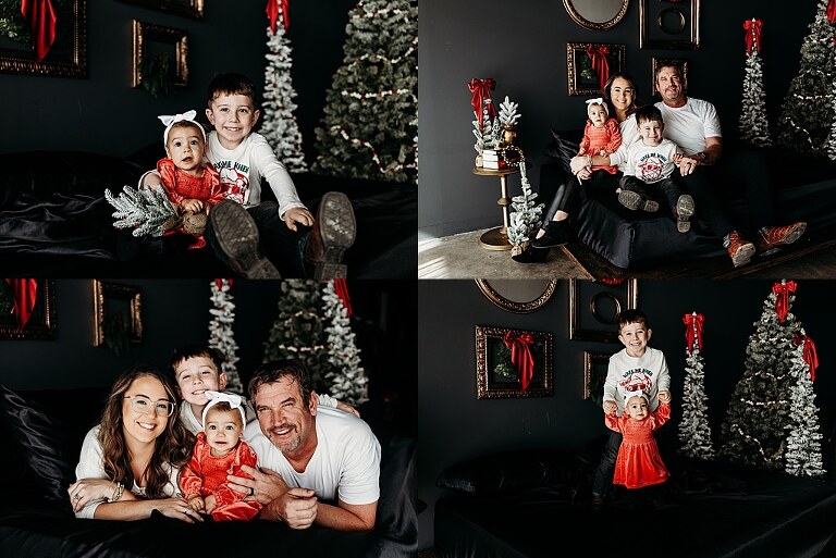 Oden family posing in a moody Christmas mini session setup with black bed, snowy trees, and nostalgic garlands in a Lake St Louis studio