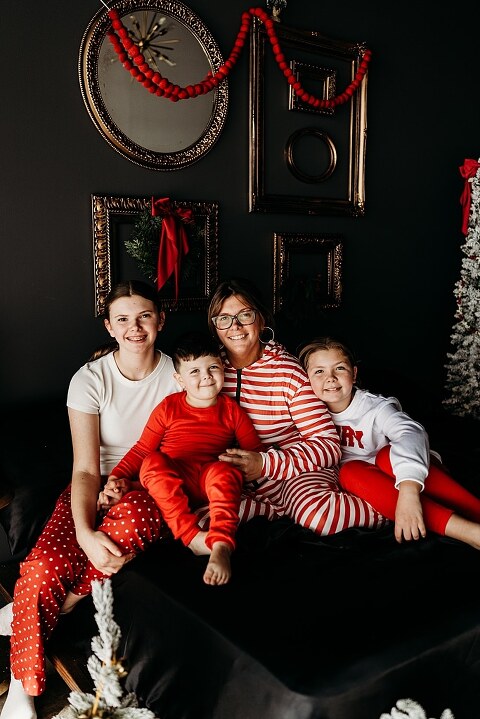 Moody Christmas mini session setup with black bed, snowy Christmas trees, cranberry and popcorn garland, and gold and red holiday accents in a Lake St Louis studio