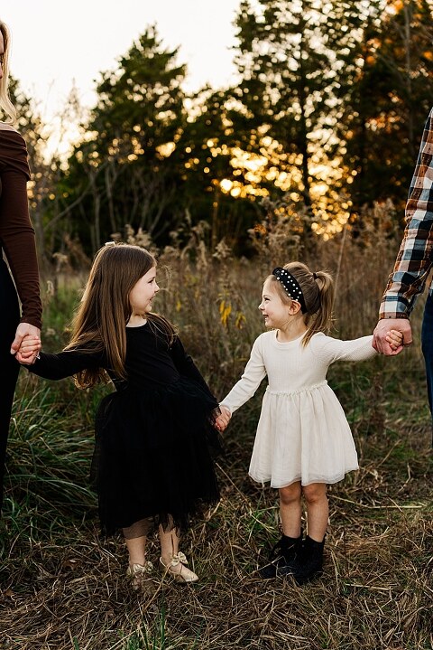 Family standing together at Towne Park in Foristell Missouri during golden hour.
Parents holding their children while laughing in an open field.
Family walking along a tree-lined path at Towne Park.
Kids smiling while standing between their parents during the session.
Close-up of Rob and Taylor hugging with soft light behind them.