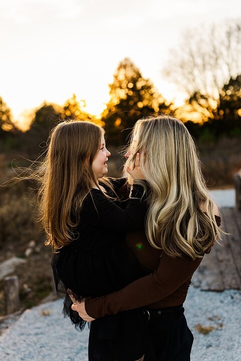 Family standing together at Towne Park in Foristell Missouri during golden hour.
Parents holding their children while laughing in an open field.
Family walking along a tree-lined path at Towne Park.
Kids smiling while standing between their parents during the session.
Close-up of Rob and Taylor hugging with soft light behind them.