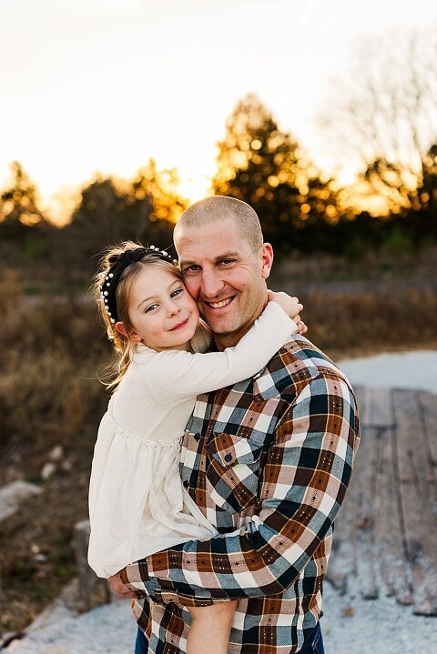 Family standing together at Towne Park in Foristell Missouri during golden hour.
Parents holding their children while laughing in an open field.
Family walking along a tree-lined path at Towne Park.
Kids smiling while standing between their parents during the session.
Close-up of Rob and Taylor hugging with soft light behind them.