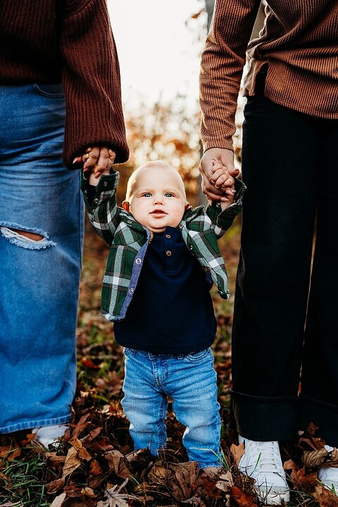 Family holding their baby during a session in High Hill Missouri.
Parents kissing their smiling little boy in warm natural light.
Baby laughing while sitting with his parents on a country path.
Family walking together through a grassy field.
Close-up of baby boy smiling during his milestone session.