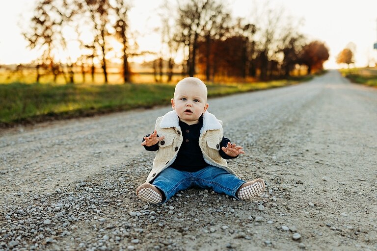 Family holding their baby during a session in High Hill Missouri.
Parents kissing their smiling little boy in warm natural light.
Baby laughing while sitting with his parents on a country path.
Family walking together through a grassy field.
Close-up of baby boy smiling during his milestone session.