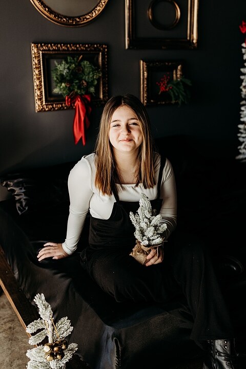 Family sitting on black bed during Christmas Mini Session with trees and garland
Parents holding newborn twins in studio with red and gold holiday details
Children sitting together on bed with Christmas trees behind them
Close up of popcorn and cranberry garland in Christmas Mini setup